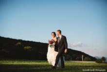 Bride-Groom-Walk-Across-Meadow-Mountian-Background